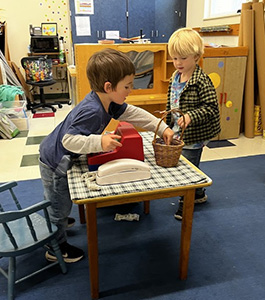 Student smiling at the camera while building a castle out of blocks