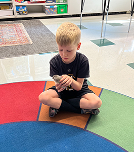 Little boy sitting on colorful classroom floor