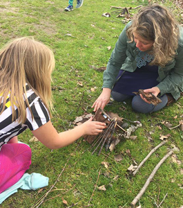 Women teaching girl how to build a fire