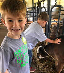 Student smiling at the camera while petting goats.